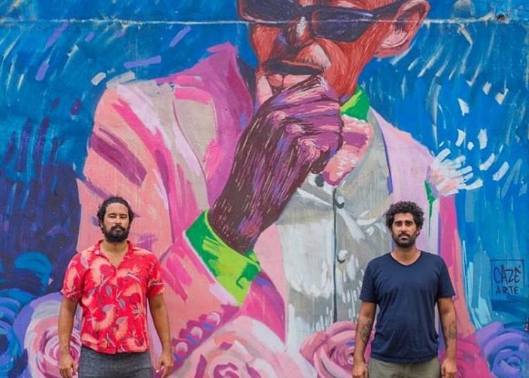 Pedro e Cazé em frente ao grafite do músico Cartola