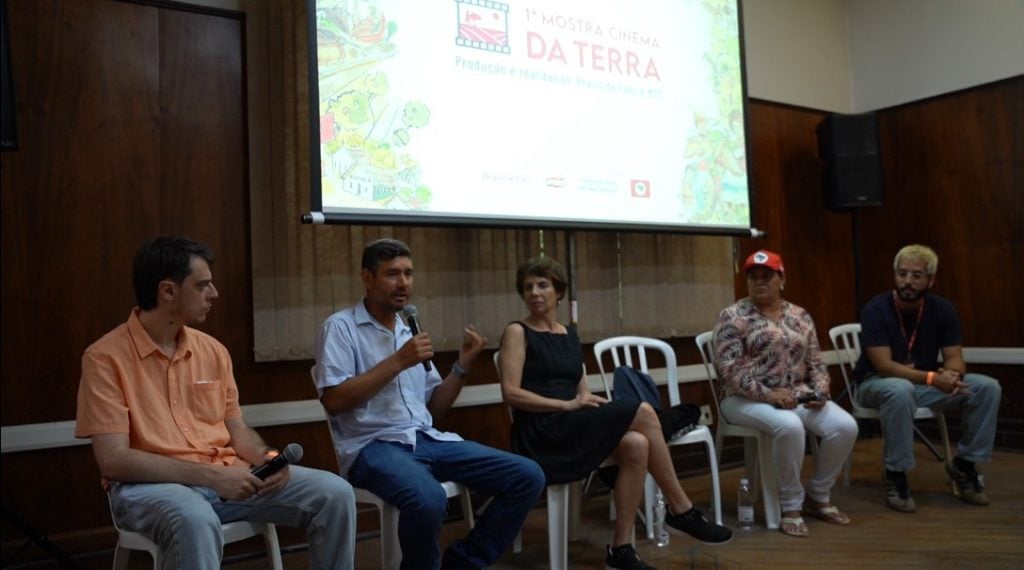 Pessoas sentadas em cadeiras, numa mesa de debate para um público, após a exibição de filmes numa mostra de cinema