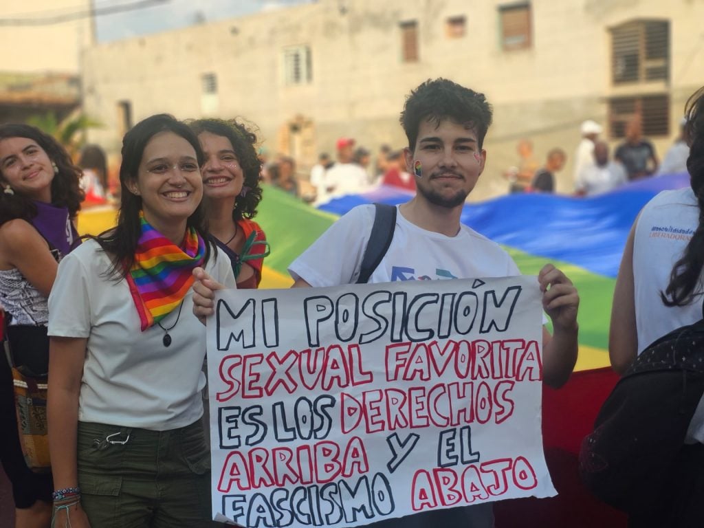 Anaclara León, junto com Verde Gil, jovens ativistas pelos direitos da comunidade LGBTIQ+, seguram um cartaz que diz: "Minha posição sexual favorita é os direitos no topo e o fascismo por baixo."